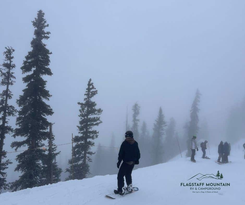Snowboarder at Arizona Snowbowl Ski resort in Flagstaff Arizona with the Flagstaff Mountain RV logo in the corner. Snowbowl near Flagstaff Mountain RV park, RV Park in Flagstaff Arizona