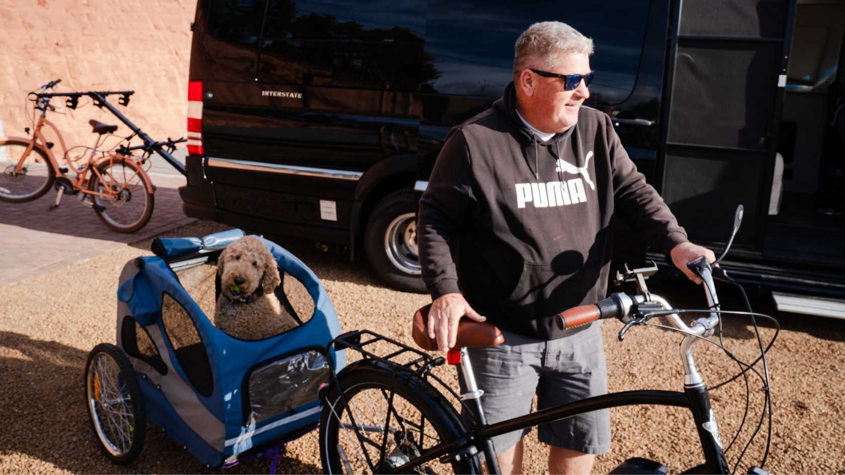 A traveler biking with their dog through a sun-dappled Flagstaff trail.