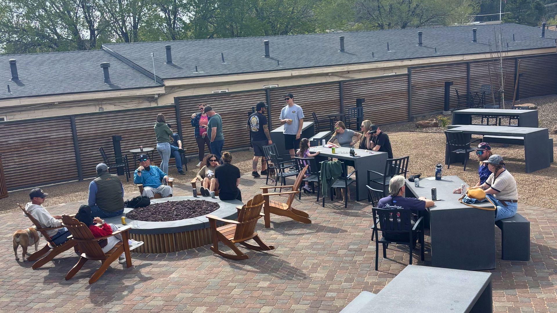 Guests relaxing around fire pit seating and patio tables at a modern RV campground in Flagstaff.
